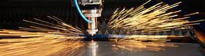 Industrieller Laserschneider im Einsatz, der Metall schneidet und dabei helle Funken sprüht.